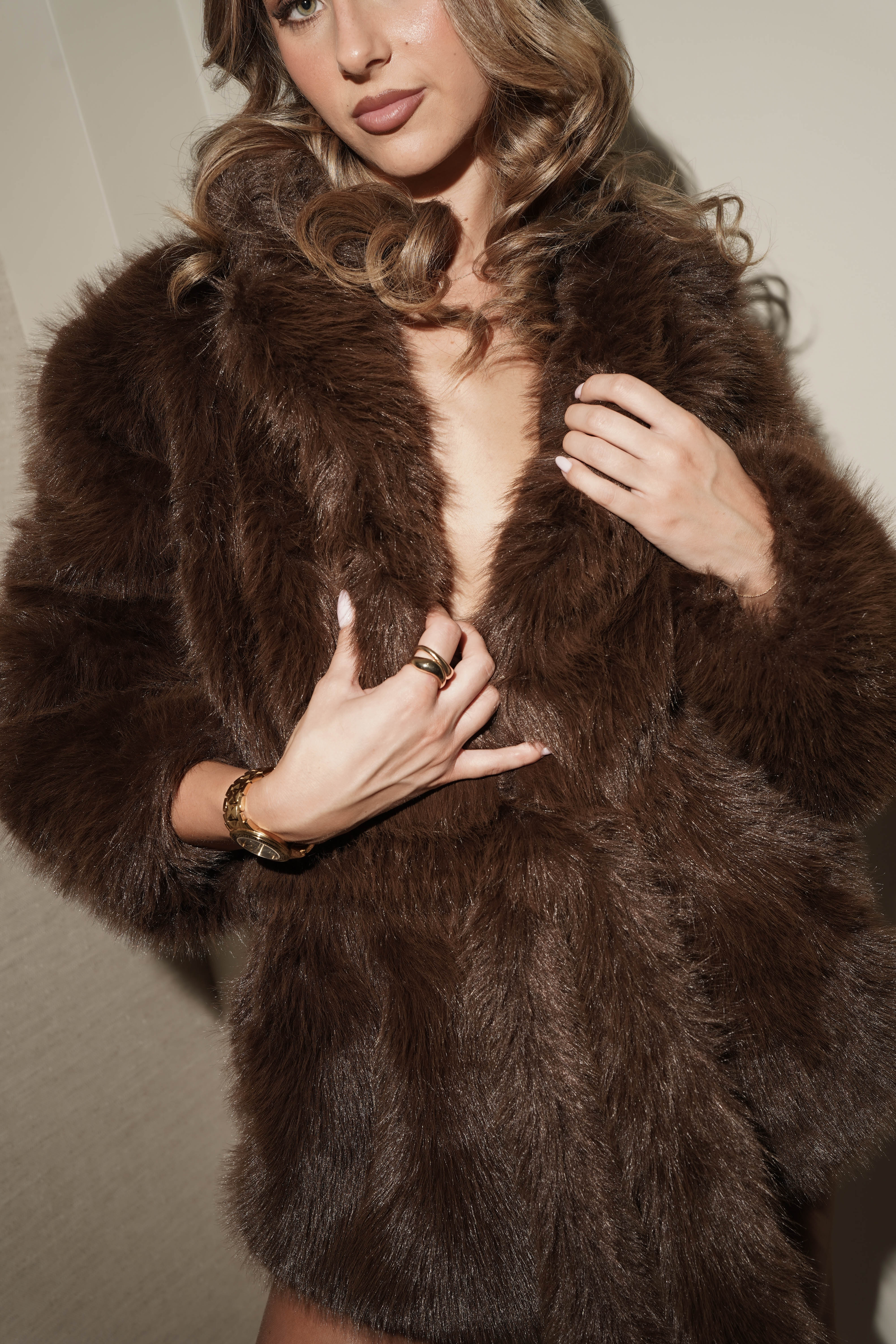 Woman wearing an Aleya new york coffee brown fur coat with a neutral background
